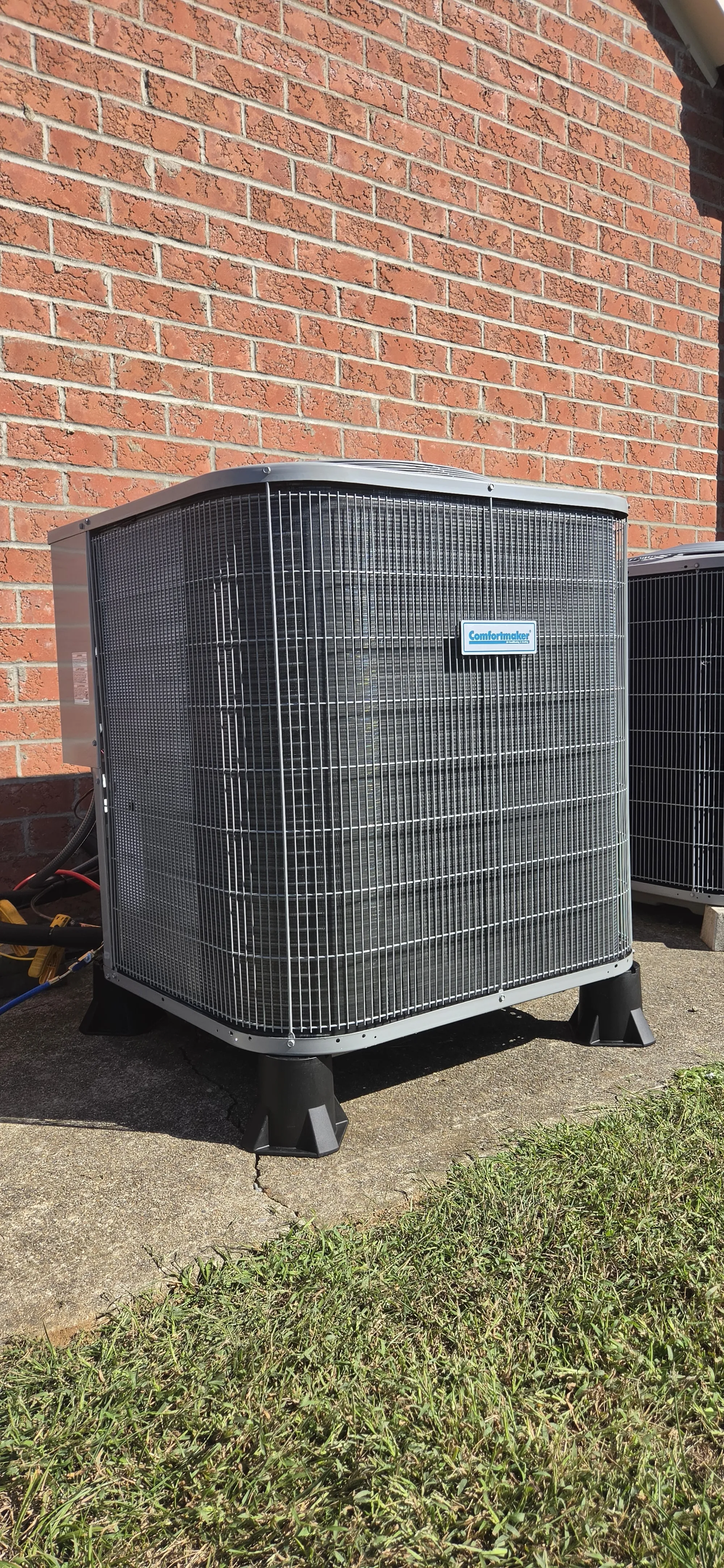 2 ton 14.3 SEER2 heat pump outdoor unit on pads beside a brick wall, HVAC job in Cincinnati, OH.