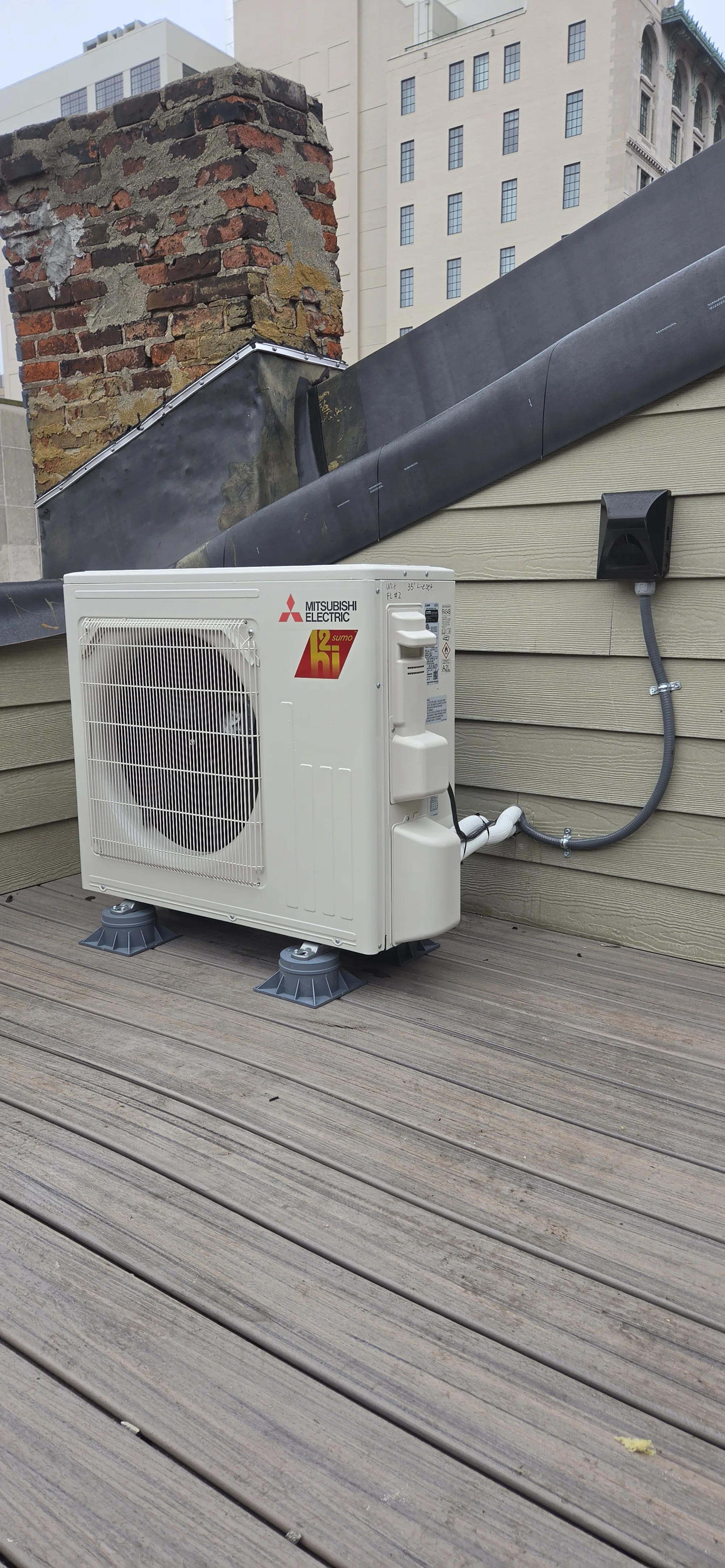 12,000 BTU mini split outdoor unit on mounting pads on a wood deck, mini split install in Cincinnati, OH.