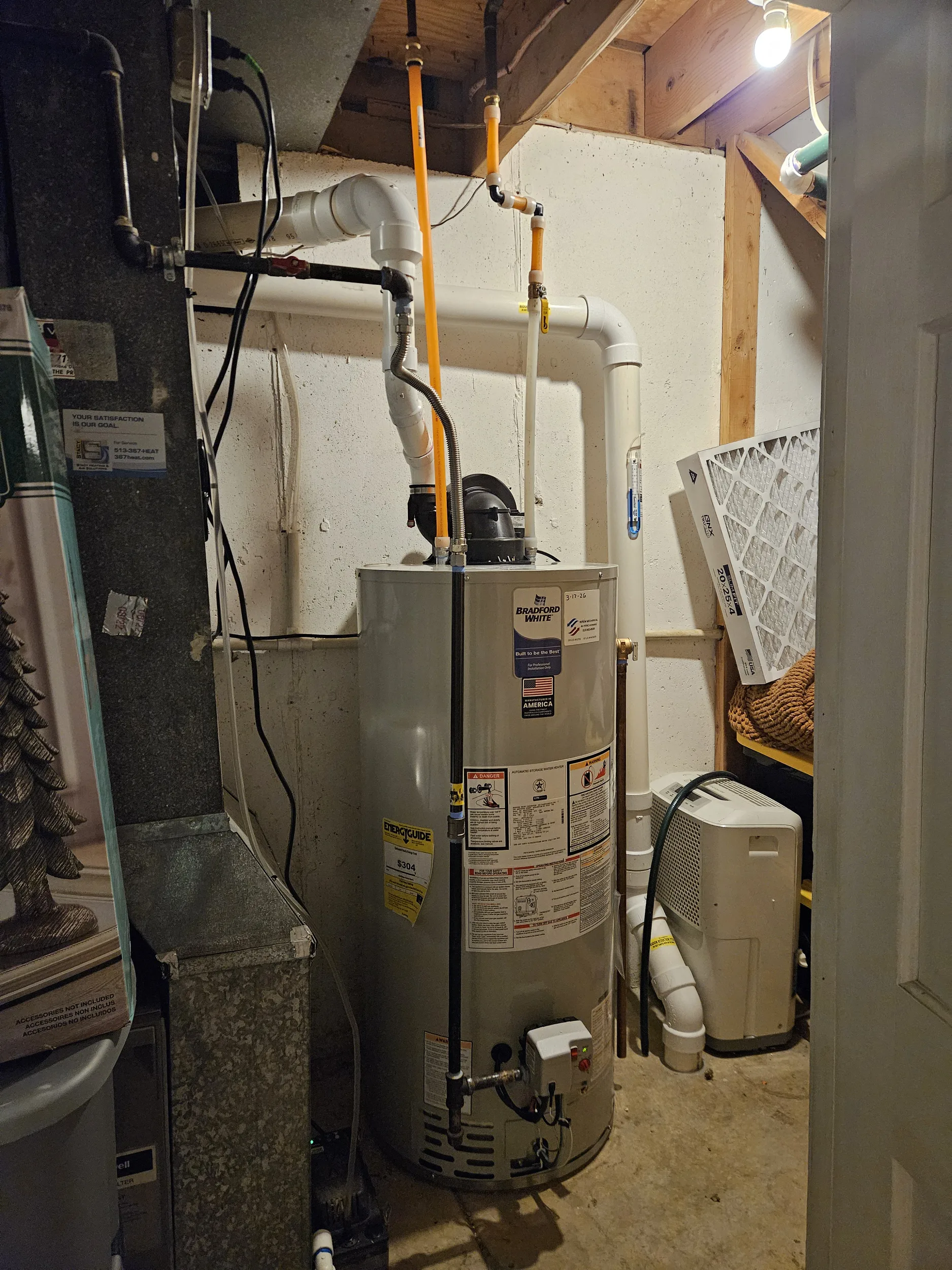 Gas tank water heater with white PVC vent piping in a basement utility room, water heater replacement in Loveland, OH.